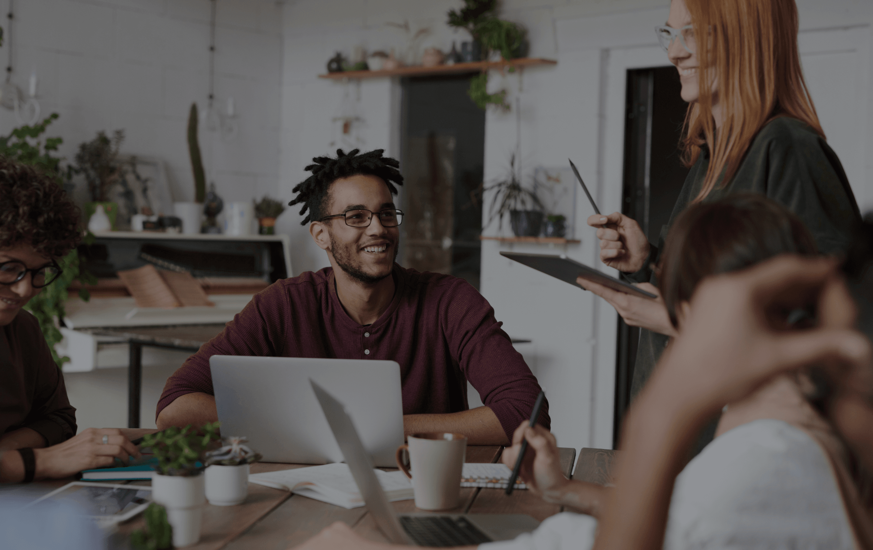 Person smiling while working with a team in a desk with personal computers