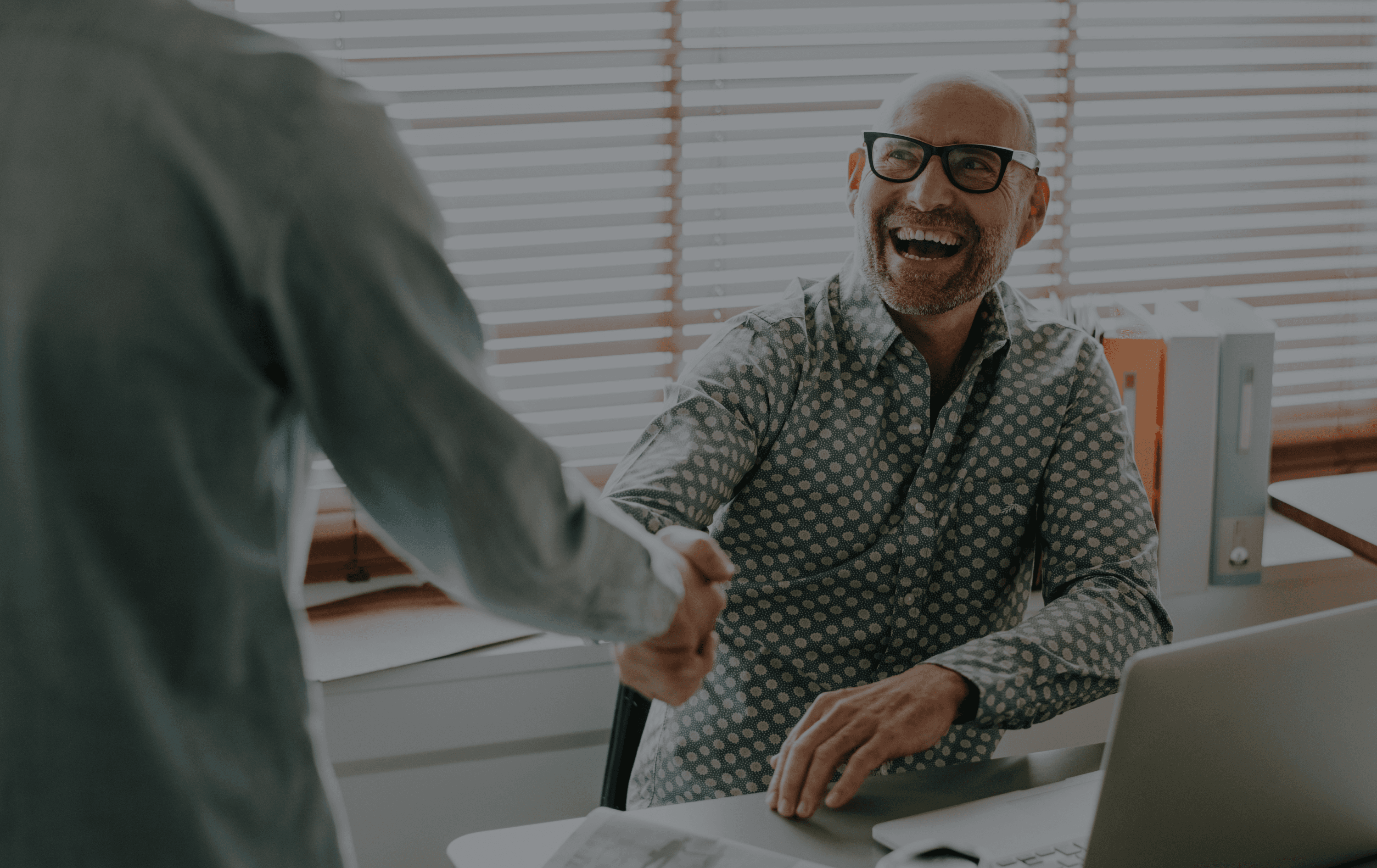 Person smiling while closing a deal by handshaking another person